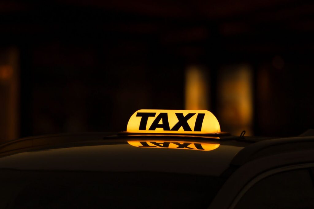 Yellow taxi sign glowing in Gothenburg night, perfect for urban travel themes.
